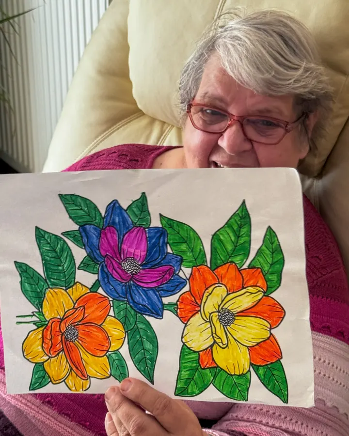 Ergotherapie: eine Bewohnerin zeigt ihr ausgemaltes Blumenbild