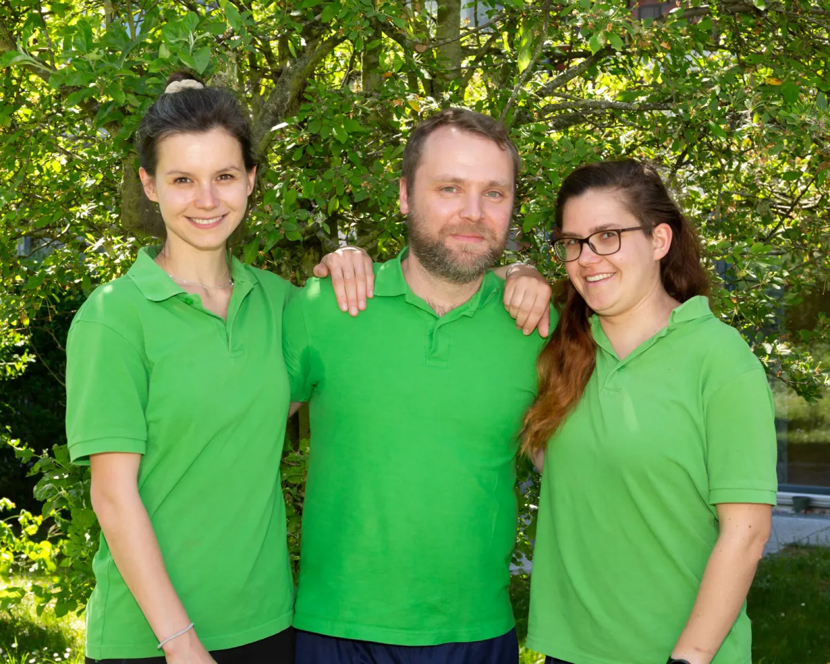 Drei Therapeutinnen und Therapeuten des Physiopark Berlin im Garten